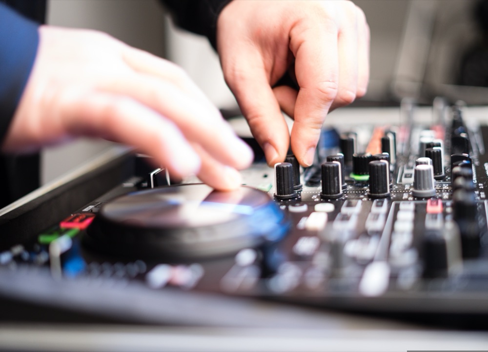 Hands working a DJ deck and mixer